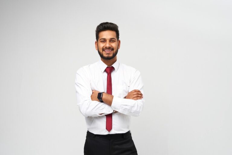 portrait-young-indian-top-manager-t-shirt-tie-crossed-arms-smiling-white-isolated-wall